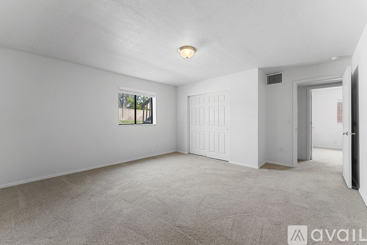 A spacious room with a carpeted floor and a window.