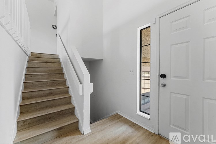 A wooden staircase with a white railing and a white door with a glass window.