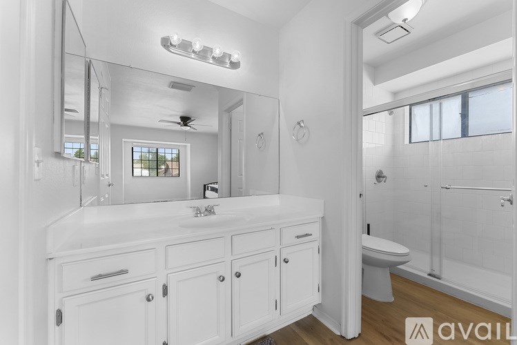 A white bathroom with a large mirror and a vanity.