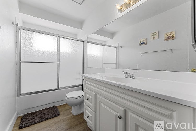 A white bathroom with a toilet, sink, and mirror.