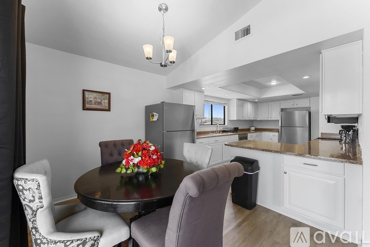 A modern kitchen with a dining table set with a floral arrangement.