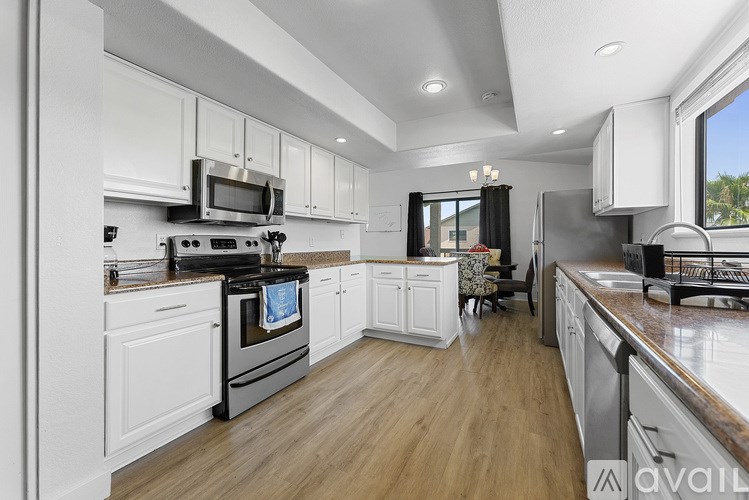 A modern kitchen with white cabinets and wooden floors.