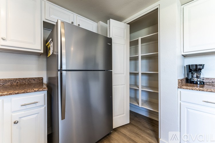 A stainless steel refrigerator is in a kitchen with white cabinets.