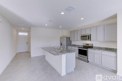 A kitchen with white cabinets and a marble island.