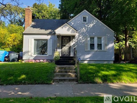 A house with a front yard and a blue tarp in the background.