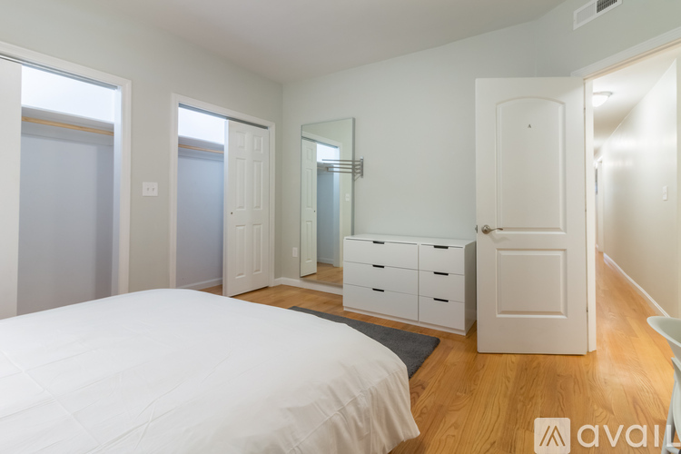 A white bathroom with a tub and a doorway leading to a bedroom.