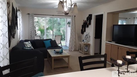 A living room with a black couch and a wooden coffee table.