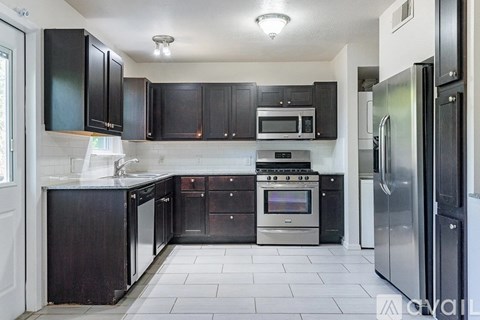 A kitchen with black cabinets and stainless steel appliances.