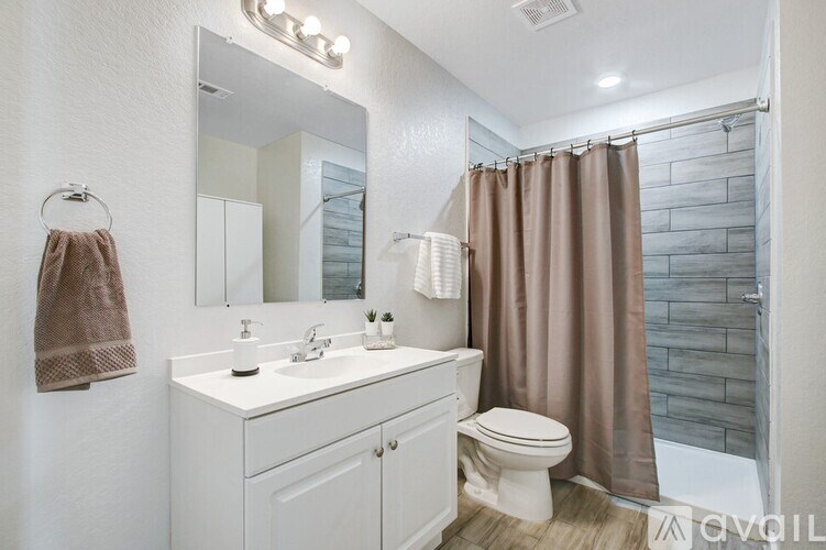 A bathroom with a white vanity and a brown shower curtain.
