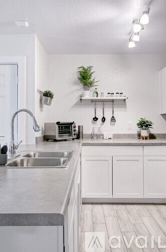 A kitchen with white cabinets and a stainless steel sink.