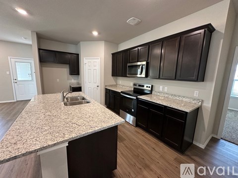 A kitchen with dark brown cabinets and a granite countertop.