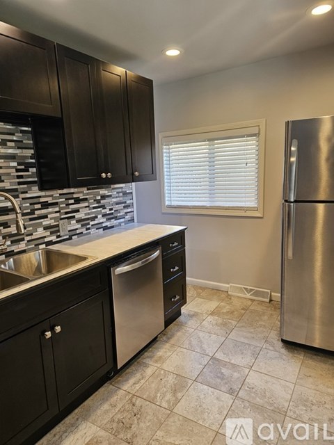 A kitchen with black cabinets and a stainless steel refrigerator.