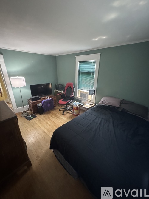 A bedroom with a bed, desk, chair, and window.