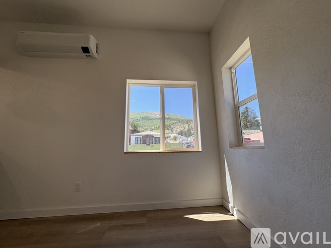 A room with a window showing a view of a house and trees outside.