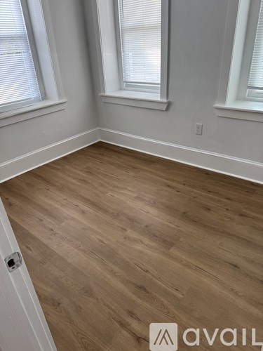 A room with wooden flooring and white walls.