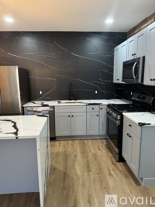 A kitchen with a marble backsplash and wooden floors.