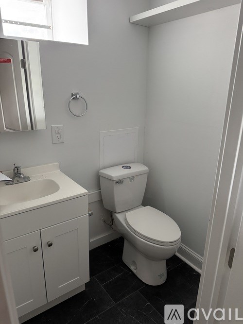 A white toilet in a bathroom with a white sink and cabinet.
