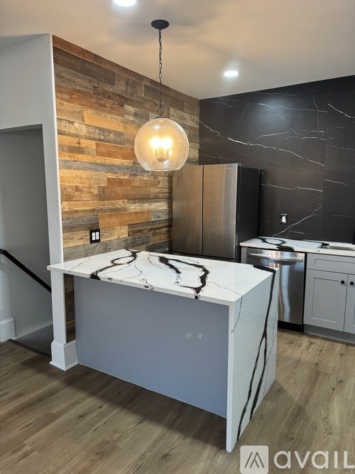 A kitchen with a marble countertop and a wooden wall.