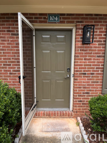 A grey door with a black mailbox on a brick wall.