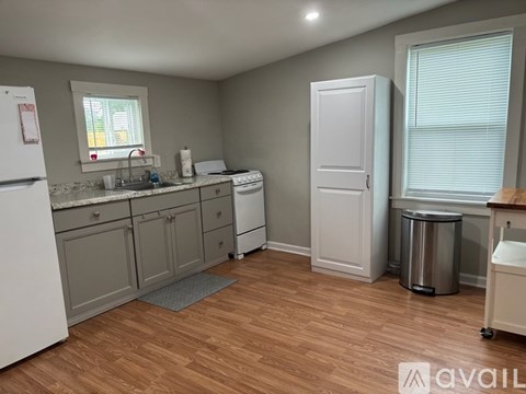 A kitchen with white appliances and wooden floors.