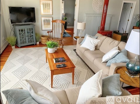 A living room with a white couch, a wooden coffee table, and a television on a cabinet.