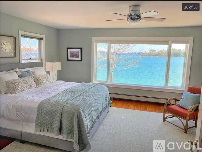 A bedroom with a large bed and a view of a body of water.