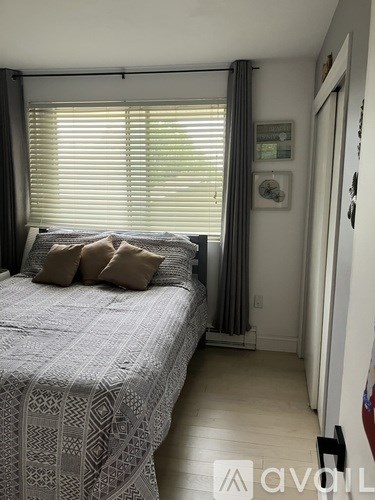 A bedroom with a bed and a window with blinds.