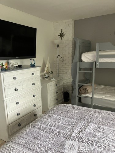A bedroom with a bed, dresser, and bunk bed.