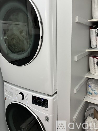 A white washing machine with a digital display and control panel is stacked on top of another similar machine.