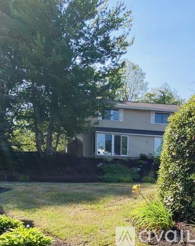 A house with a well-kept lawn and trees in the background.