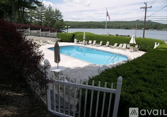 A pool surrounded by white chairs and a white fence.