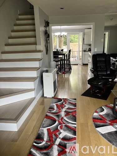 A living room with a staircase and a dining area.