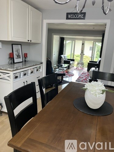 A kitchen with a wooden table and chairs in front of a welcome sign.