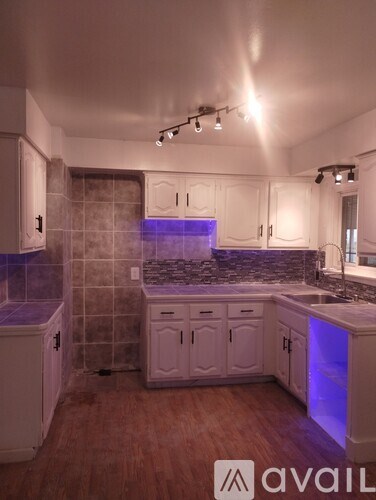 A kitchen with white cabinets and a purple light.