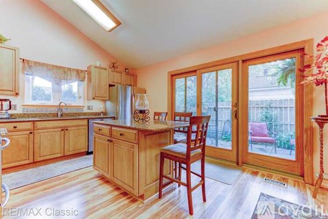 A kitchen with wooden cabinets and a table with a chair.