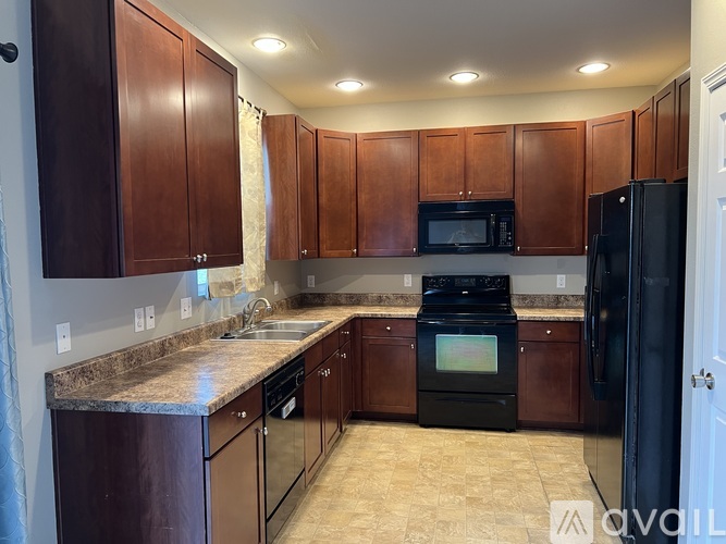 A kitchen with brown cabinets and black appliances.