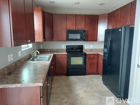 A kitchen with brown cabinets and black appliances.