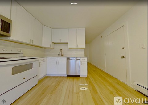A kitchen with white cabinets and a wooden floor.