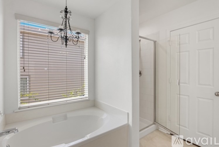 A white bathroom with a tub and a chandelier.