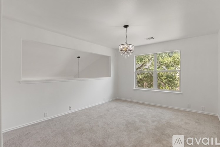 A room with a chandelier and a window with a view of trees.