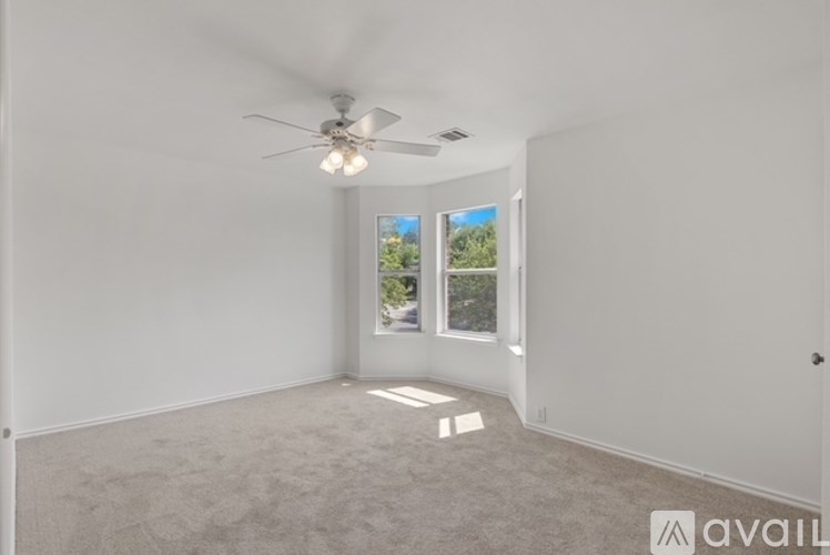 A room with a ceiling fan and carpeted floor.