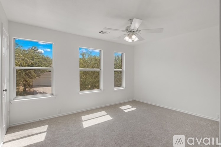 A room with a ceiling fan and three windows.