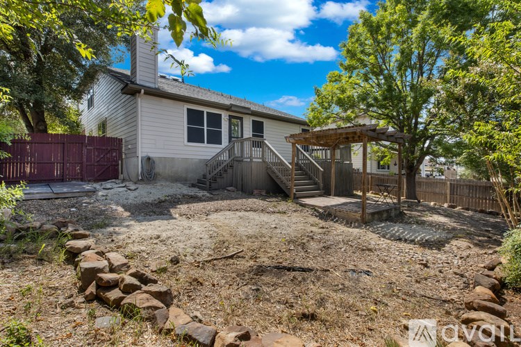A house with a backyard that has a rock wall and a tree.
