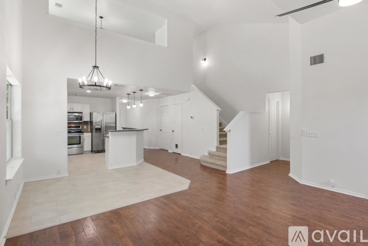 A spacious open-concept living area with a kitchen in the background.
