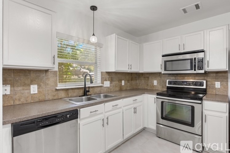 A kitchen with white cabinets and a black dishwasher.