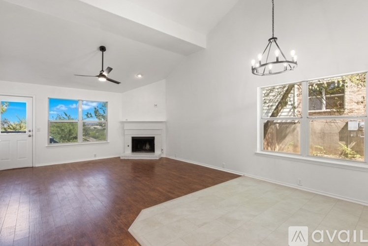 A spacious living room with a fireplace and a ceiling fan.
