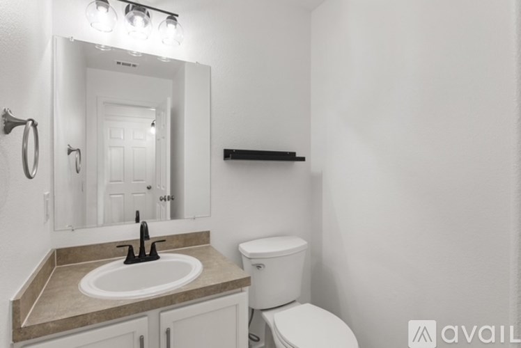 A bathroom with a sink, toilet, and mirror.