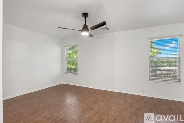 A room with a ceiling fan and two windows.