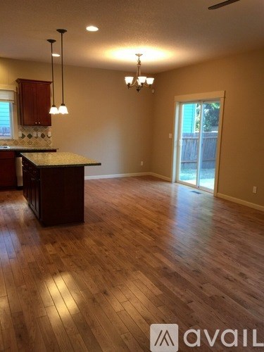 A room with wooden flooring and a kitchen area with a counter and cabinets.