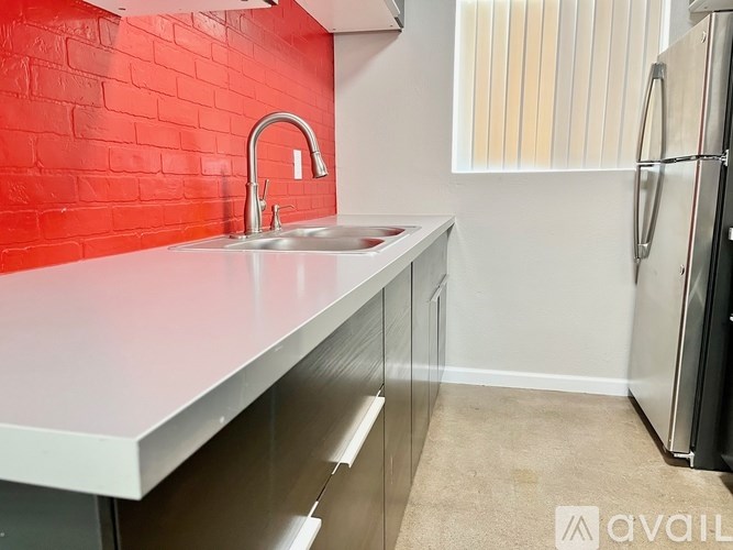 A kitchen with a red wall and a white countertop.